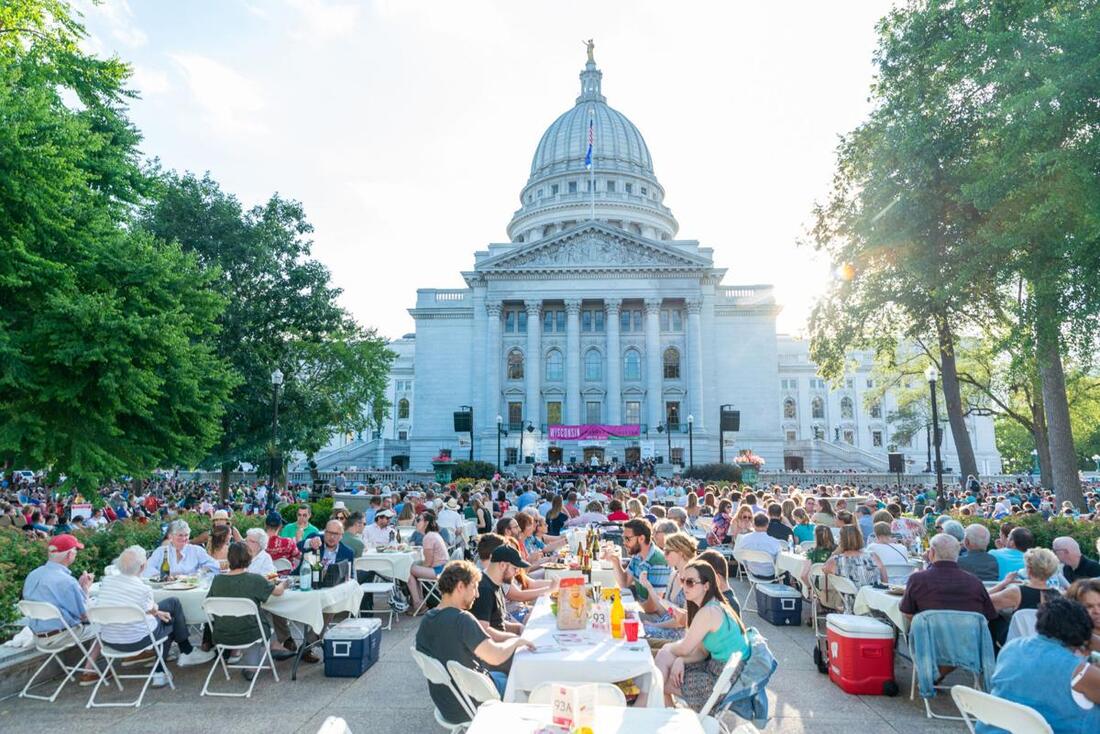 A photo of a large group of people seated outside of the Capitol building in Madison, WI 