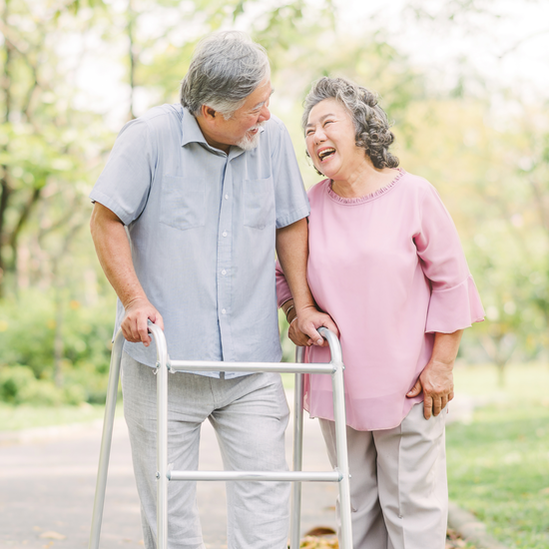 A photo of an elderly couple. One person is using a walker