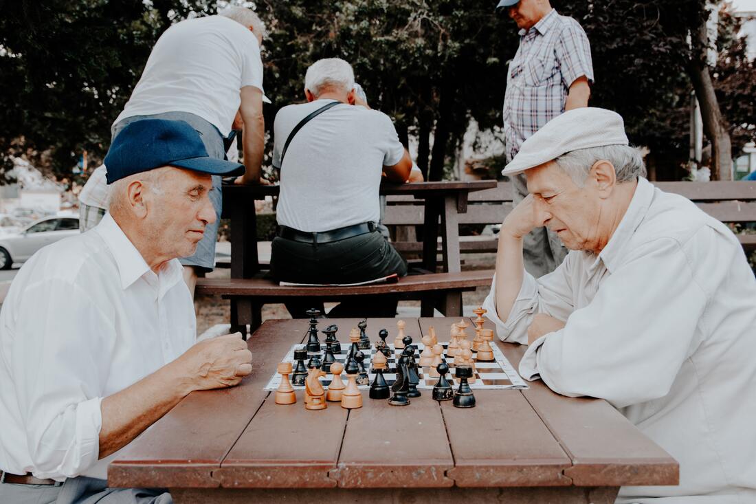 Two older people playing chess together.