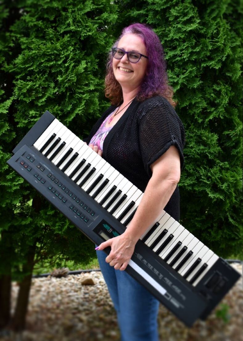 A photo a Shar posing with her keyboard outdoors.